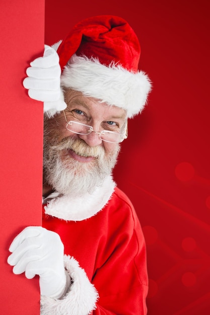 Immagine composita di babbo natale che dà una occhiata dal tabellone rosso