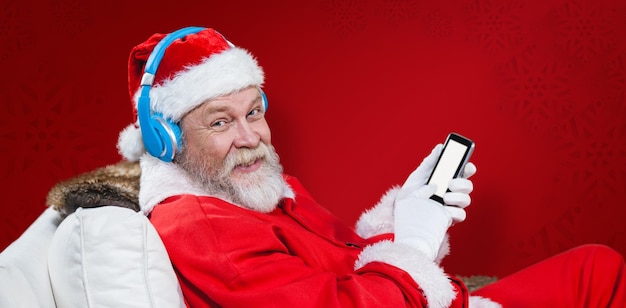 Immagine composita di Babbo Natale con le cuffie tramite telefono cellulare