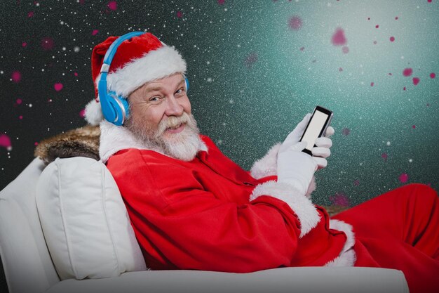 Immagine composita di Babbo Natale con le cuffie tramite telefono cellulare