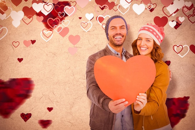 Immagine composita di giovani coppie felici che tengono la carta a forma di cuore