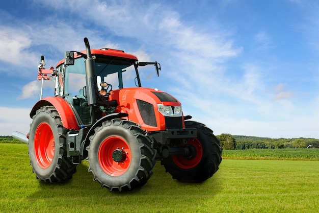 Immagine composita di un trattore generico agricolo rosso moderno su un campo verde in una giornata di sole