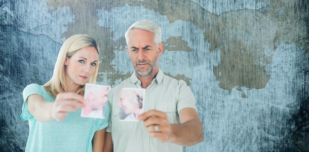 Immagine composita di una coppia infelice che tiene due metà della fotografia strappata