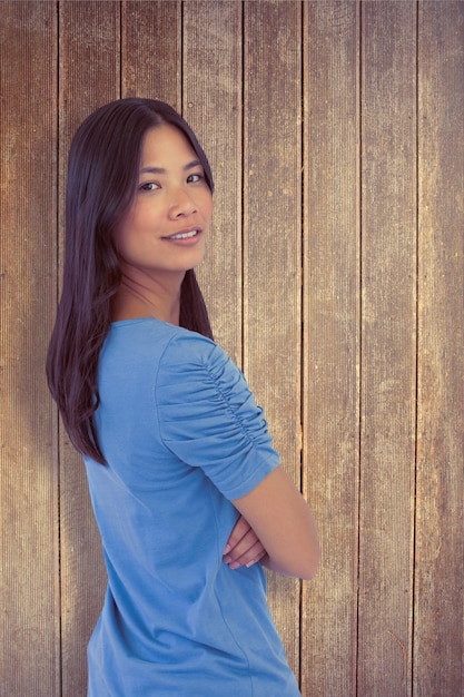 Immagine composita di una donna asiatica sorridente con le braccia incrociate che guarda sopra la sua spalla