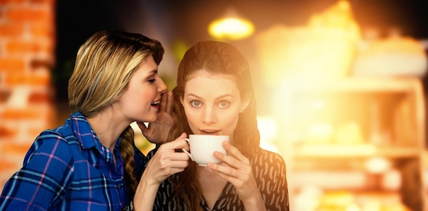 Immagine composita di una donna che sussurra nell'orecchio di un'altra donna mentre si beve una tazza di caffè