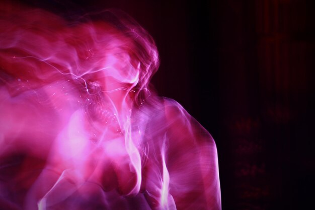 Immagine composita digitale di una donna in luce rosa su sfondo nero