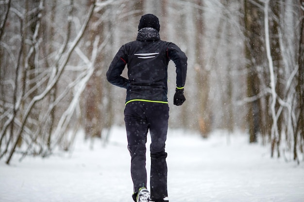 Immagine dal retro dell'uomo in abbigliamento sportivo in esecuzione in inverno