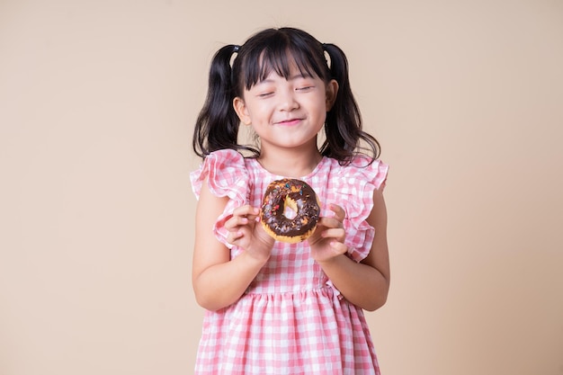 Immagine del bambino asiatico che mangia la torta della tazza sullo sfondo