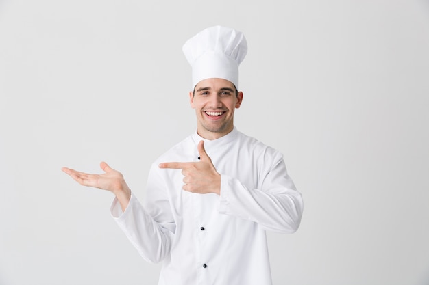 Immagine del bello chef eccitato giovane uomo al chiuso isolato su sfondo bianco muro di puntamento.