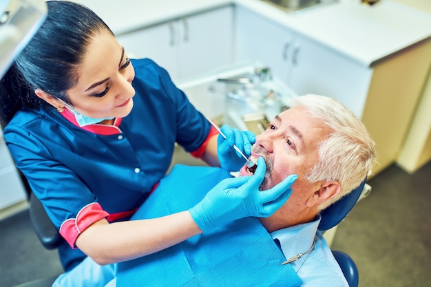 Immagine del dentista che usa uno specchio angolato mentre esamina i denti del paziente