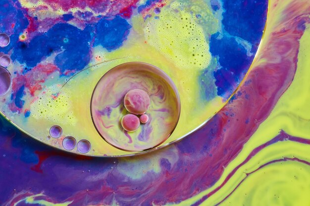 Immagine del dettaglio di una superficie liquida colorata con motivi circolari e piccole sfere