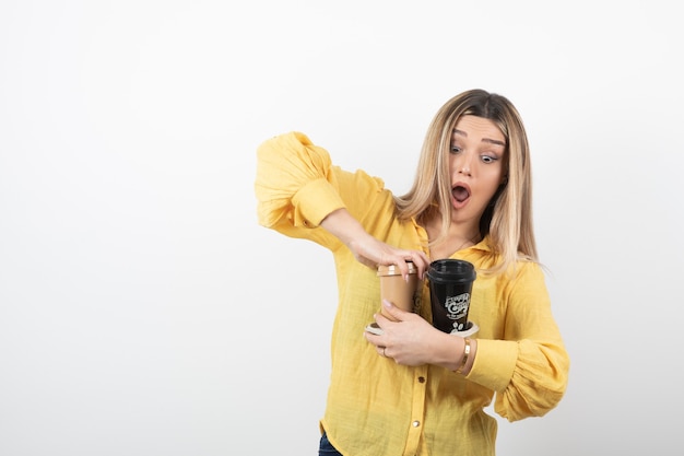 Immagine del giovane che tiene le tazze di caffè su bianco.