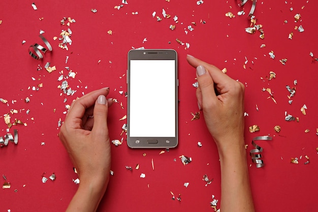 Immagine del modello delle mani che tengono telefono cellulare bianco su rosso festivo