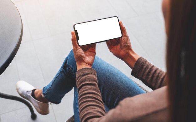 Immagine del modello di una donna che tiene il telefono cellulare con lo schermo del desktop bianco vuoto