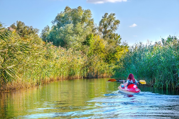 Immagine del paesaggio di una ragazza dai capelli rossi in una canoa