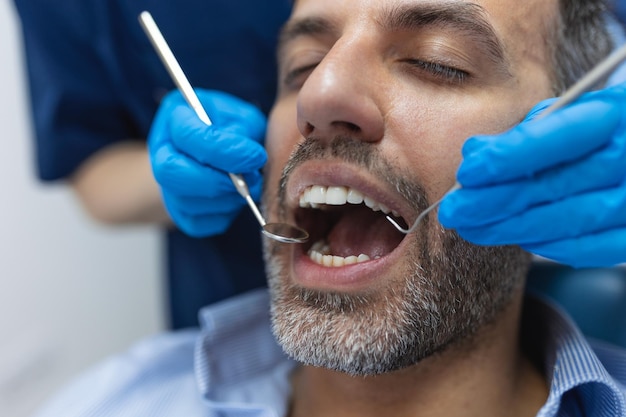 Immagine del paziente maschio soddisfatto seduto nella poltrona del dentista al centro medico mentre il medico professionista si ripara i denti