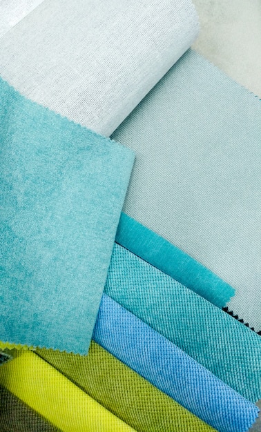 Immagine del primo piano dell'assortimento di campioni di tessuto per mobili imbottiti. Pezzi di materiale blu e verde. Sfondo astratto primo piano closeup