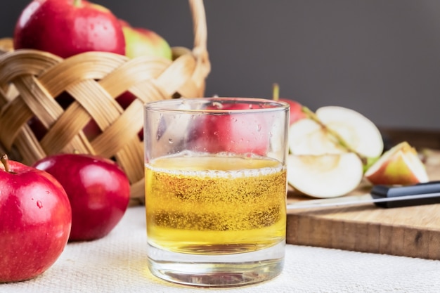Immagine del primo piano della bevanda del cidre e delle mele succose mature sulla tavola di legno rustica. Bicchiere di sidro fatto in casa e mele biologiche coltivate localmente