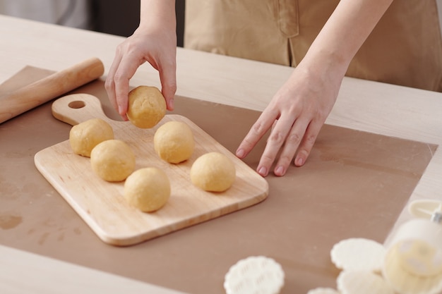 Immagine del primo piano della donna che mette i panini di pasta sul tagliere di legno