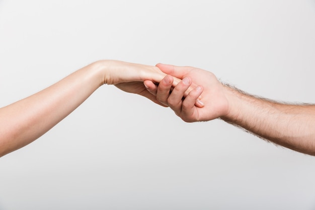 Immagine del primo piano della mano di una donna della tenuta del signore isolata sopra la parete bianca della parete.