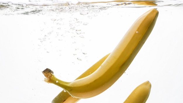 Immagine del primo piano delle banane mature fresche che cadono e che spruzzano in acqua