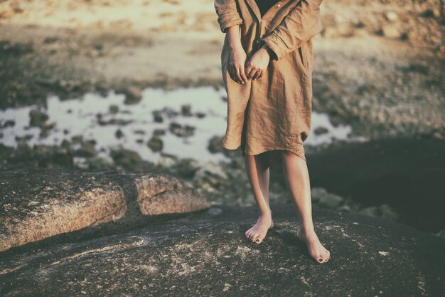 Immagine del primo piano delle gambe di una donna in piedi sulla roccia sulla spiaggia