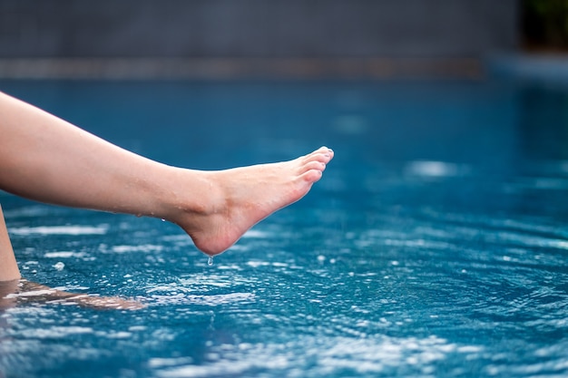 Immagine del primo piano delle gambe e dei calci a piedi nudi e dell'acqua in ammollo nella piscina