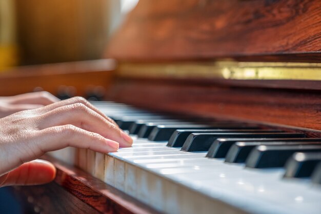 Immagine del primo piano delle mani che giocano un pianoforte a coda in legno vintage