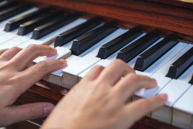 Immagine del primo piano delle mani che giocano un pianoforte a coda in legno vintage