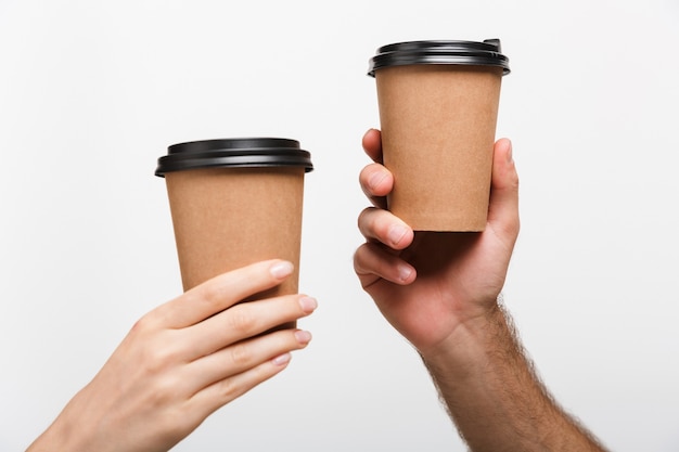 Immagine del primo piano delle mani di una donna e di un uomo isolate sopra le tazze bianche della tenuta della parete della parete con caffè.