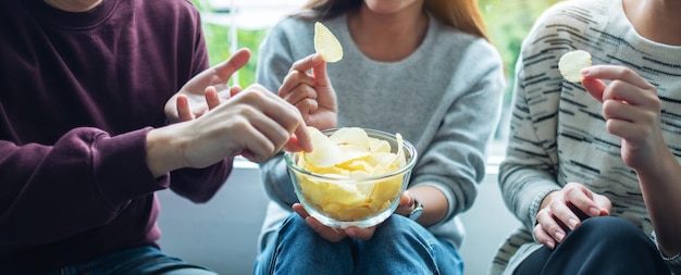 Immagine del primo piano di amici che condividono e mangiano patatine a casa insieme