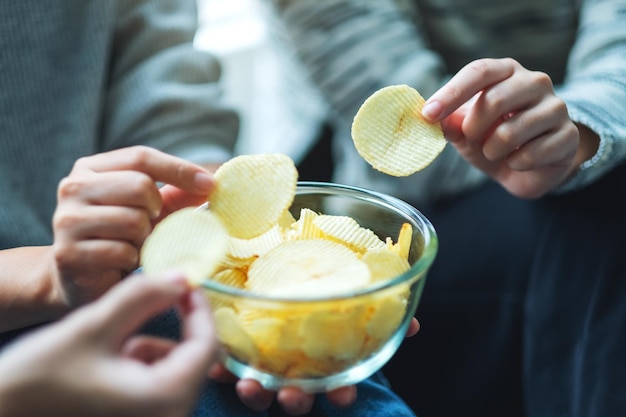 Immagine del primo piano di amici che condividono e mangiano patatine a casa insieme