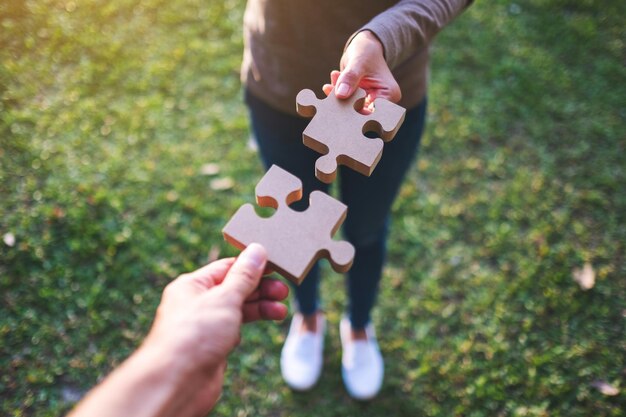 Immagine del primo piano di due persone che tengono e mettono insieme un pezzo di puzzle di legno