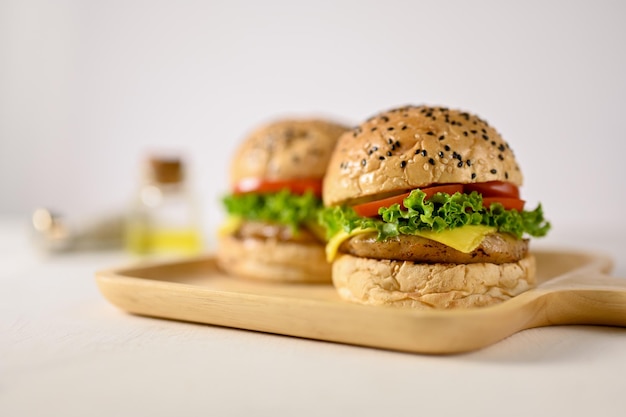 Immagine del primo piano di un gustoso hamburger di manzo sul vassoio di legno su sfondo bianco