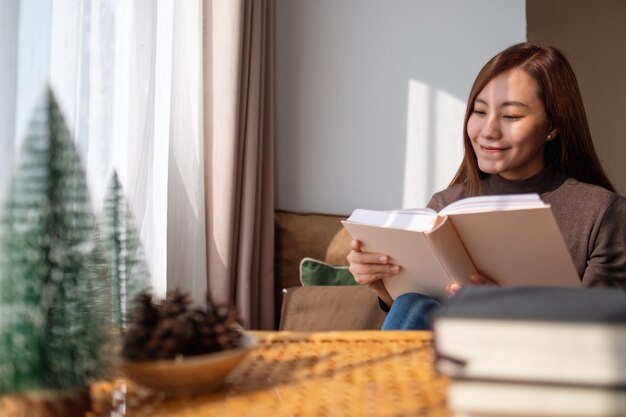 Immagine del primo piano di un libro di lettura della giovane e bella donna asiatica a casa