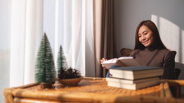 Immagine del primo piano di un libro di lettura della giovane e bella donna asiatica a casa