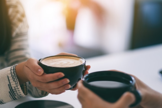 Immagine del primo piano di un uomo e una donna che tengono insieme due tazze di caffè