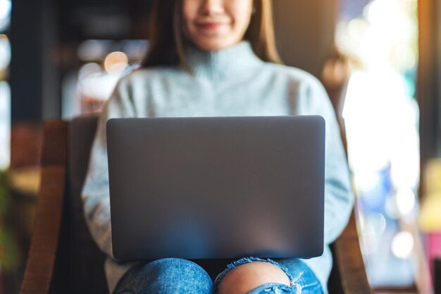 Immagine del primo piano di una bella donna asiatica che lavora al computer portatile nella caffetteria