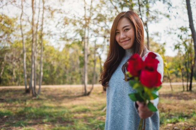 Immagine del primo piano di una bella donna asiatica che tiene e dà un fiore di rose rosse il giorno di San Valentino