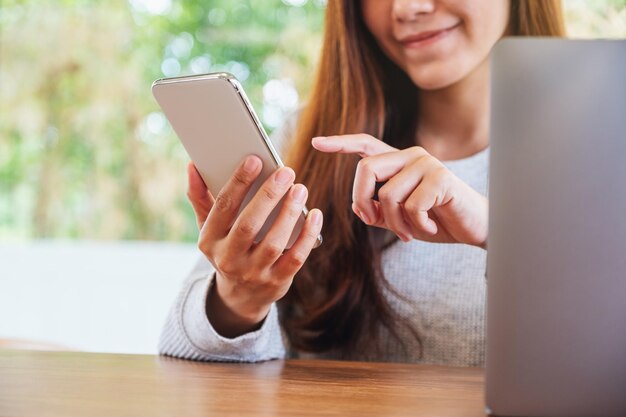 Immagine del primo piano di una bella donna asiatica che tiene e usa il cellulare