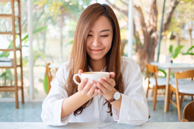 Immagine del primo piano di una bella donna asiatica che tiene una tazza di caffè caldo