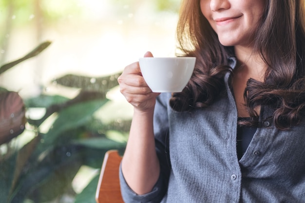 Immagine del primo piano di una bella donna che tiene e beve caffè caldo al bar