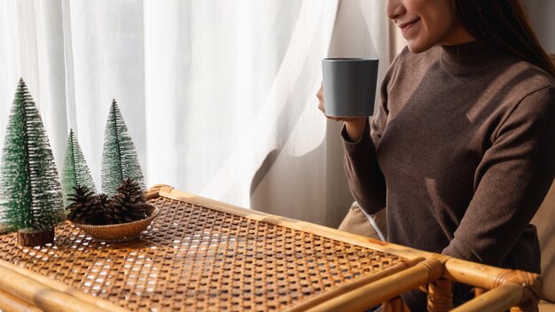 Immagine del primo piano di una bella giovane donna asiatica che beve caffè caldo a casa al mattino