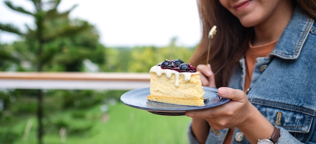 Immagine del primo piano di una bella giovane donna asiatica che mangia cheesecake ai mirtilli