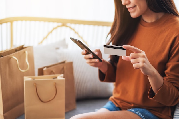 Immagine del primo piano di una bellissima giovane donna che utilizza il telefono cellulare e la carta di credito per lo shopping online