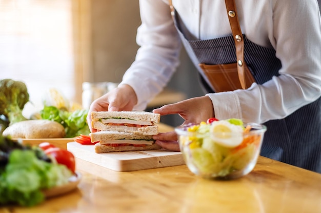 Immagine del primo piano di una cuoca che cucina e tiene in mano un pezzo di panino integrale in cucina