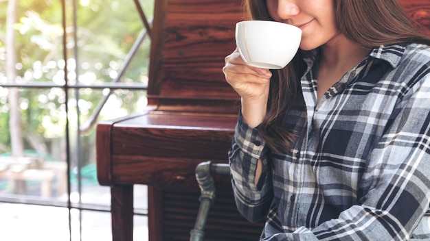 Immagine del primo piano di una donna asiatica che tiene una tazza di caffè prima di bere