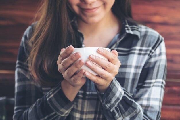 Immagine del primo piano di una donna asiatica che tiene una tazza di caffè prima di bere