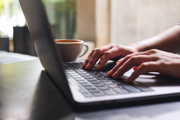 Immagine del primo piano di una donna che lavora e digita sulla tastiera del computer portatile sul tavolo