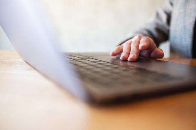 Immagine del primo piano di una donna che lavora e tocca il touchpad del computer portatile su un tavolo di legno