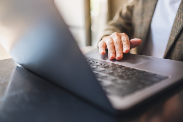 Immagine del primo piano di una donna che lavora e tocca il touchpad del laptop sul tavolo